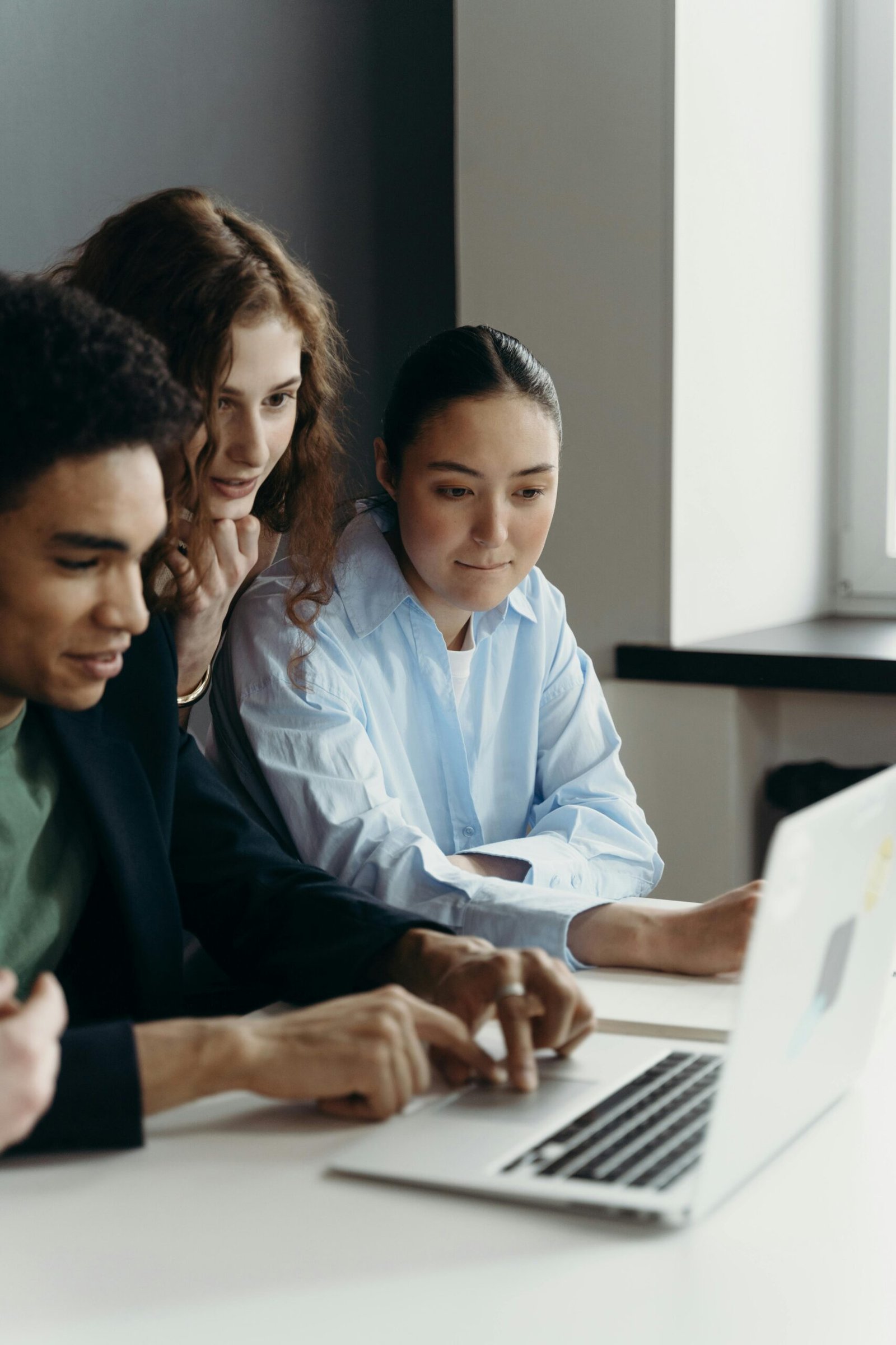 A diverse team of professionals collaborating on a laptop in an office setting.